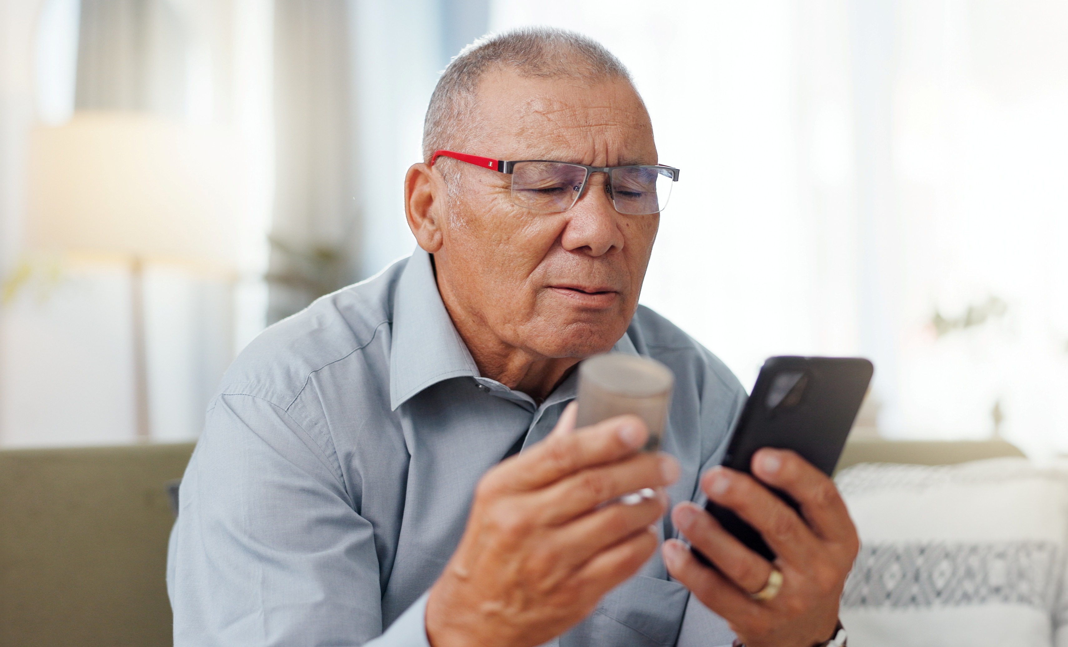 Senior man with glasses looking at credit card and phone
